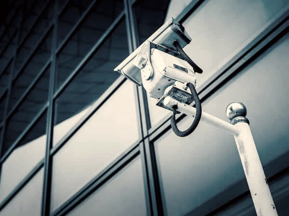 Bullet camera on a glass facade bracket at dusk